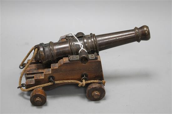 An early 20th century bronze model of a Naval cannon, on wooden trunnion base, length 25cm